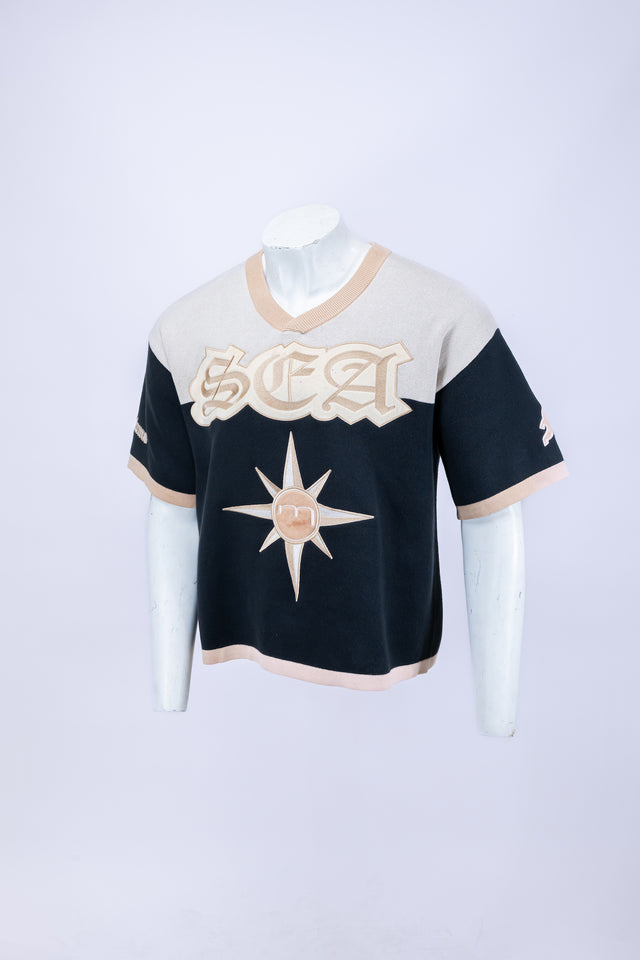 Mannequin wearing a beige and navy Mediums Collective SEA 206 Knit V neck sports jersey with a SEA Velour embroidery design on a white background mariners merch, mlb, near me