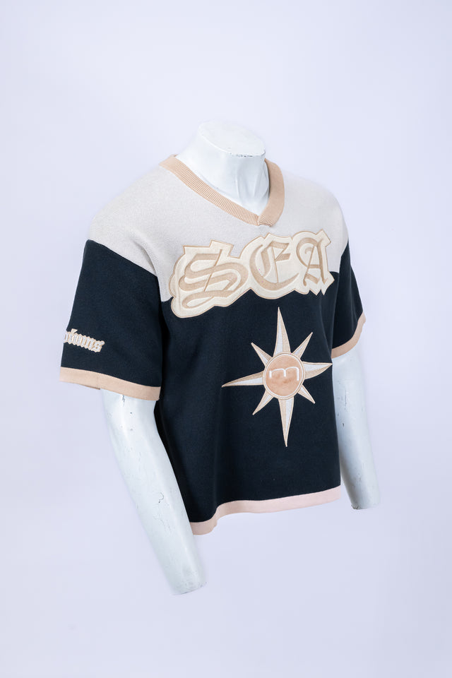 Mannequin wearing a beige and navy Mediums Collective SEA 206 Knit V neck sports jersey with a SEA Velour embroidery design on a white background. MLB, mariners merch, 90's, near me