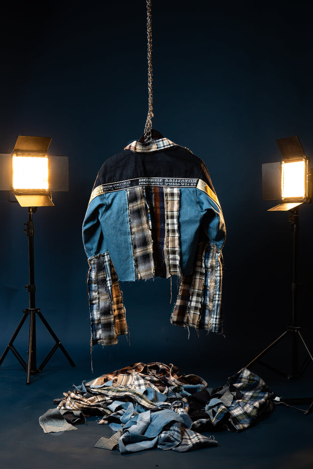 A Seattle-inspired patchwork jacket built from mixed denim, layered flannel, and signature Mediums detailing. The Seattle Fever Dream Flannel/Denim Jacket combines light blue and black denim with plaid and striped flannel panels for a bold reconstructed look rooted in Seattle streetwear style. Designed with a cropped silhouette, elongated flannel sleeve extensions, chest flap pockets, and raw exposed seams, this piece delivers texture, contrast, and movement from every angle.
