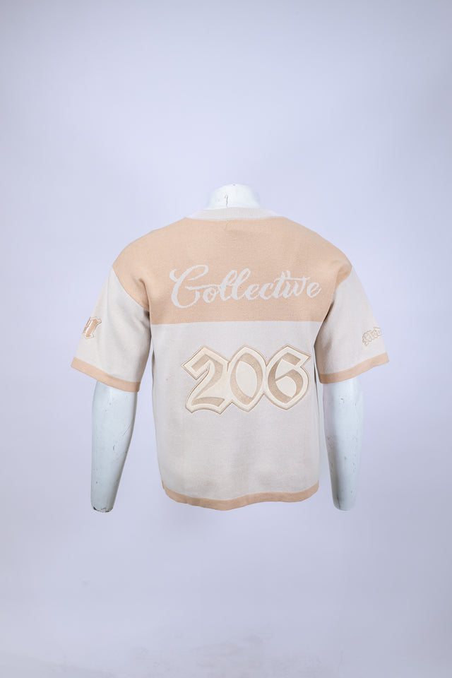 Mannequin wearing a beige and white Mediums Collective SEA 206 Knit V neck sports jersey with a SEA Velour embroidery design on a white background